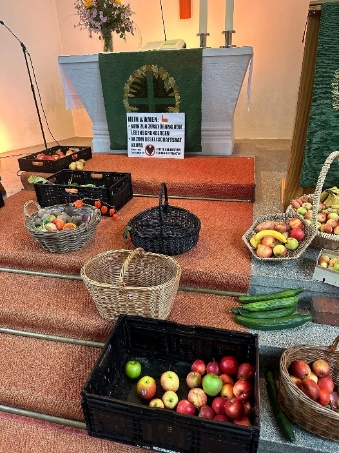 Ein Bild von einem Altar, Obst, Blumensträuße.